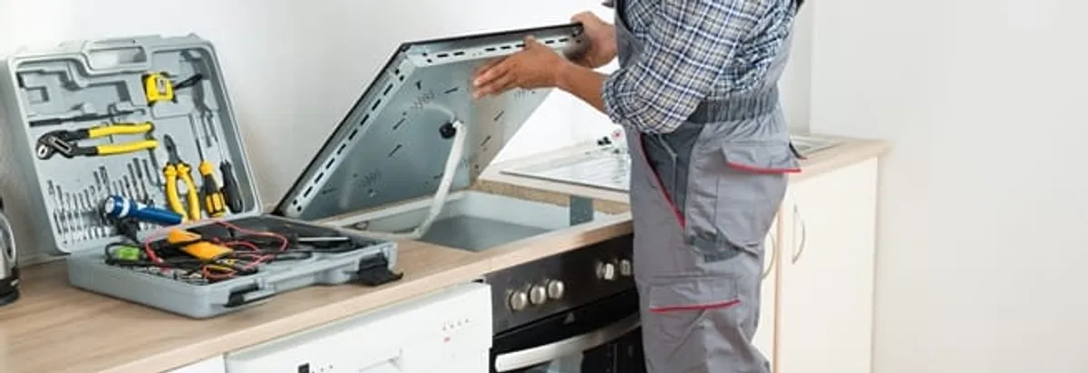 Cooktop repair technician lifting a built-in stovetop for service in Irvine, CA