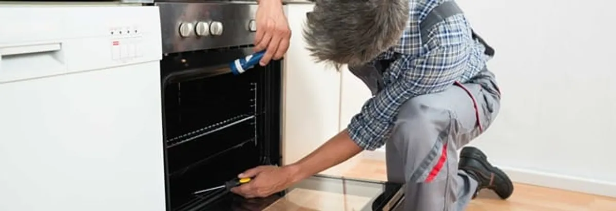 Oven repair technician inspecting and servicing an electric oven in Irvine, CA