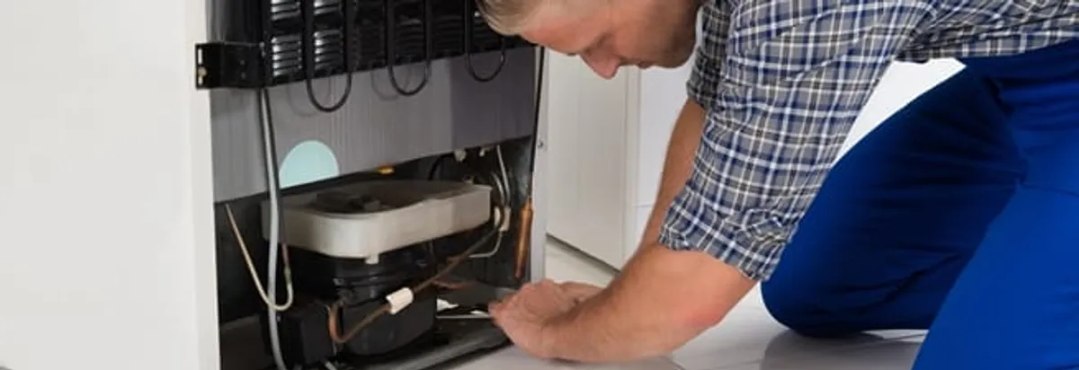 Refrigerator repair technician servicing the compressor and condenser area in Irvine, CA