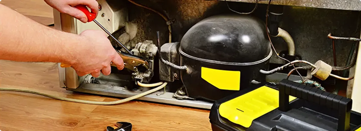 Refrigerator repair technician fixing the compressor and wiring in Irvine, CA